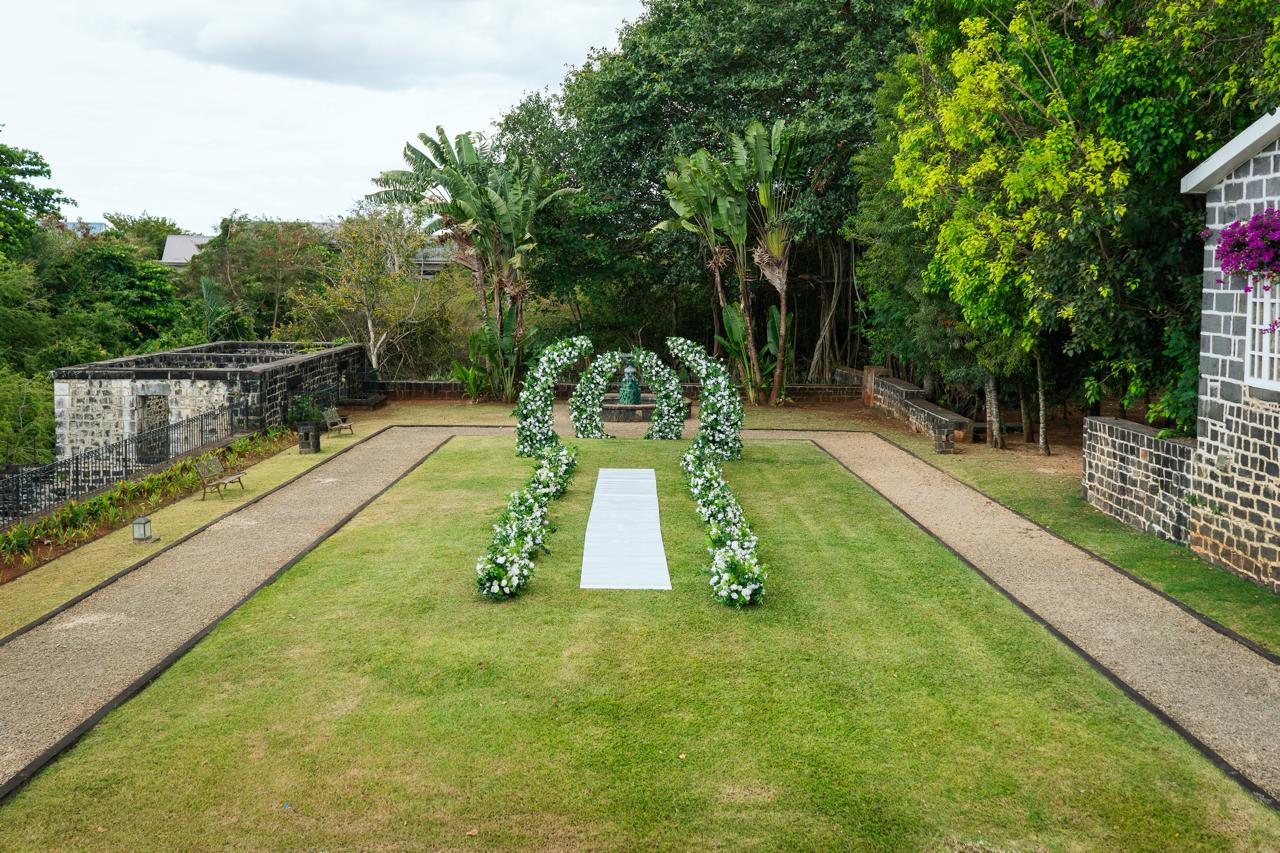 Garden wedding ceremony setup with arches and aisle